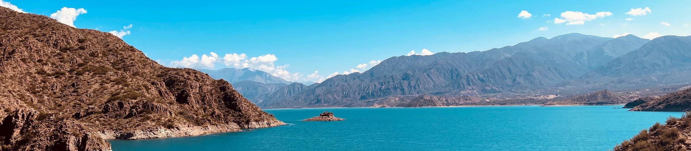 Turquoise lake surrounded by brown mountains under a blue sky
